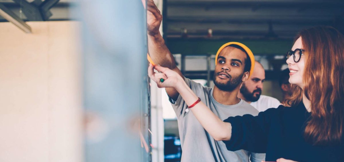 Une homme et une femme collent des post-it sur un tableau