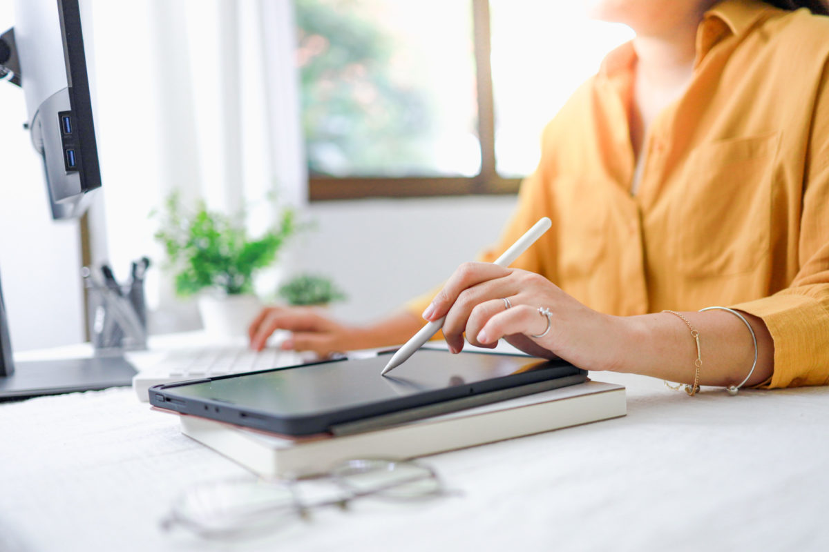 Une femme écrit sur une tablette avec un stylet